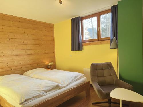 ein Schlafzimmer mit einem Bett, einem Stuhl und einem Fenster in der Unterkunft Appartements Skida in Reith bei Kitzbühel