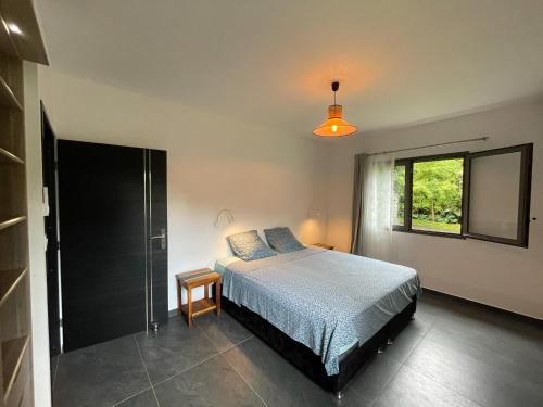 um quarto com uma cama e uma janela em Villa Les Jardins de la Trinité em Saint-Philippe
