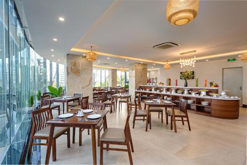 un restaurant avec des tables et des chaises en bois ainsi qu'un bar dans l'établissement Capecia Danang Hotel and Apartment, à Đà Nẵng