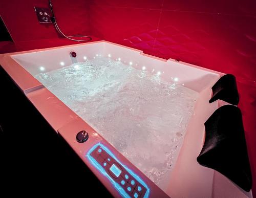 a pink bath tub with a remote control in it at Le Confiden'spa Loft 55m2 Jacuzzi - Billard - Cheminée - Terrasse in Hoenheim