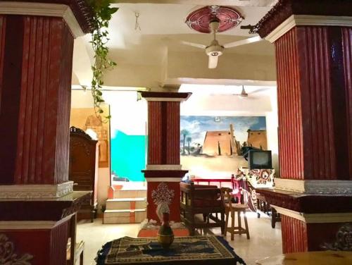 een woonkamer met rode zuilen en een kamer met een tafel bij SWEET HOSTEL LUXOR in Luxor