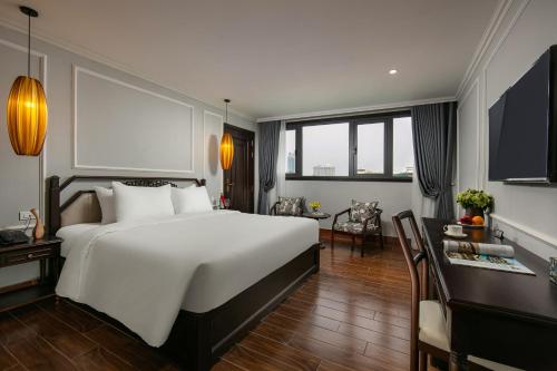 a bedroom with a large white bed and a desk at Salute Premium Hotel & Spa in Hanoi