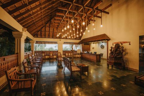 una sala da pranzo con tavoli e sedie in legno di Aadisaktthi Leisure Resort, Kovalam a Trivandrum