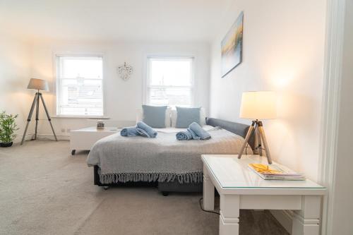 - une chambre avec un lit, une table et deux fenêtres dans l'établissement Light and airy 1 bedroom flat 700m from the Beach, à Bournemouth