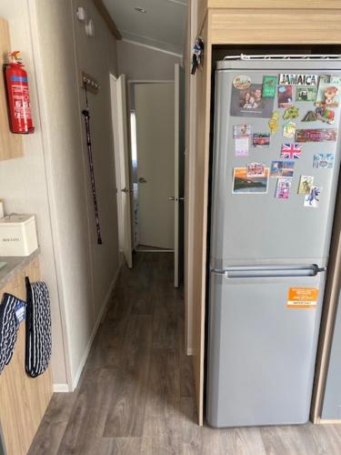 a kitchen with a refrigerator with magnets on it at Duffy's Den - Parkdean California Cliffs - Fulmar 45 in Scratby