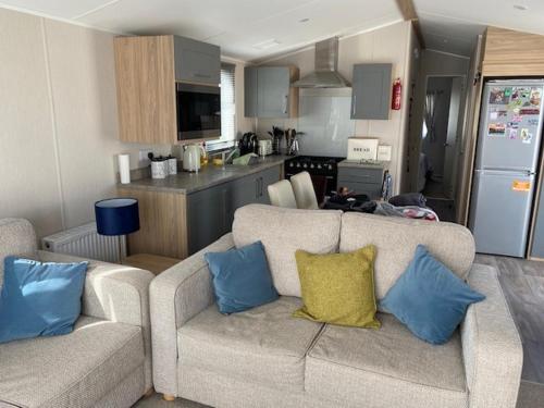 ein Wohnzimmer mit 2 Sofas und einer Küche in der Unterkunft Duffy's Den - Parkdean California Cliffs - Fulmar 45 in Scratby