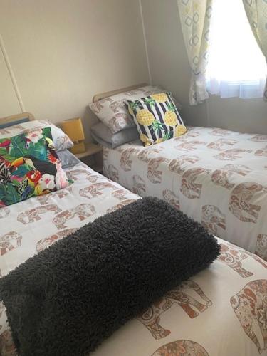 a bedroom with two beds and a black rug at Duffy's Den - Parkdean California Cliffs - Fulmar 45 in Scratby