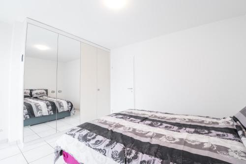 a white bedroom with a bed and a white cabinet at 3.5 Room Apartment in Würenlos
