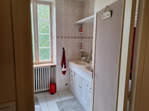 une salle de bain blanche avec un lavabo et une fenêtre dans l'établissement Communication Cheval, à Montaigu-de-Quercy