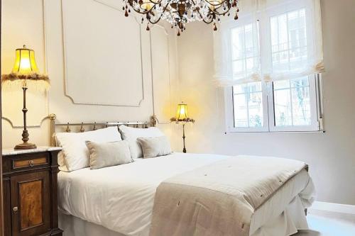 1 dormitorio con 1 cama con lámpara de araña y 2 ventanas en Magnifico Alojamiento Con Encanto En El Centro, en Santander
