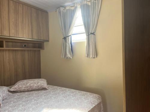a bedroom with a bed and a window with curtains at Edícula aconchegante 100m do Mar in Sombrio