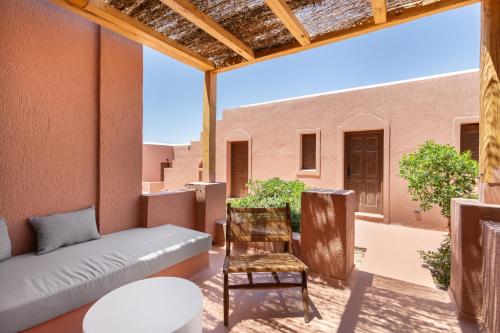 a patio with a couch and a chair on a balcony at Akre Hotel - Designed for Adults in Naxos Chora
