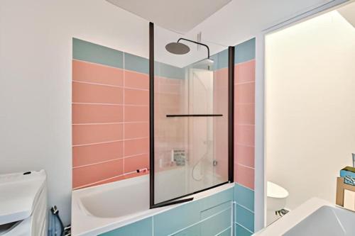 La salle de bains est pourvue d'une baignoire et d'une douche en verre. dans l'établissement Soleil du canal Saint Martin, à Paris