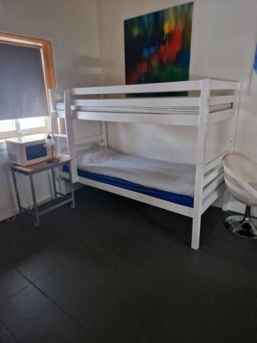 białe łóżko piętrowe w pokoju ze stołem w obiekcie Lilla Stuga w mieście Moheda