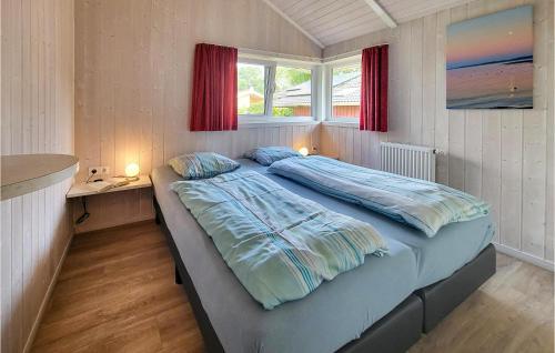 Schlafzimmer mit einem Bett mit blauer Bettwäsche und einem Fenster in der Unterkunft Strandblick 11 - Dorf 1 in Travemünde