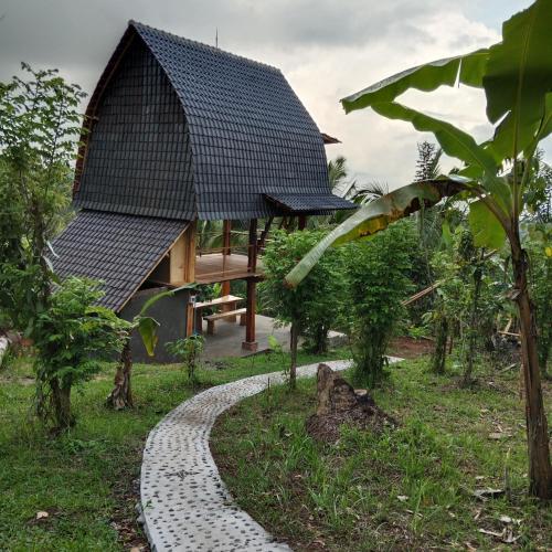 a house with a black roof and a walkway at Bali jungle cabin in Jatiluwih