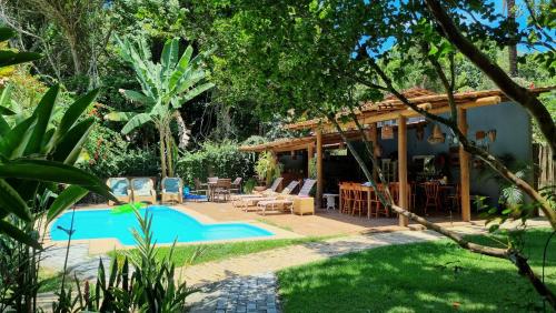 un patio trasero con piscina y una casa en Vila Pitanga Trancoso, en Trancoso