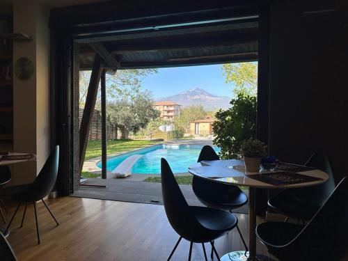 a dining room with a table and chairs and a pool at Ottomood B&B and Apartments in Tremestieri Etneo
