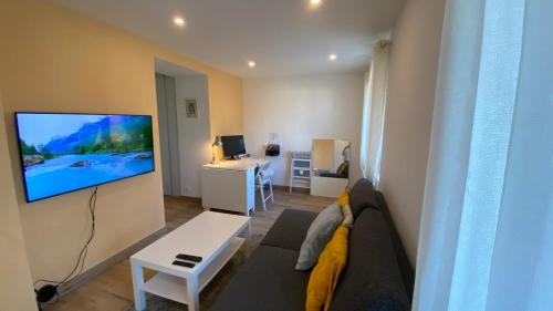 a living room with a couch and a tv on a wall at Modern and well done flat Geneva - self check-in in Saint-Genis-Pouilly