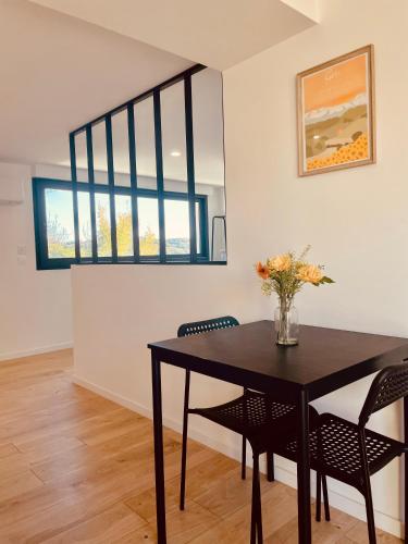 a dining room table with chairs and a vase with flowers at T1 bis rénové au centre d’Auch in Auch