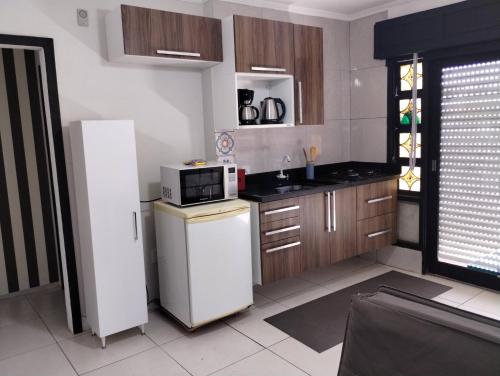 a kitchen with a white refrigerator and a microwave at Hostap de frente com sacada in Porto Alegre