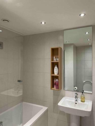 a bathroom with a sink and a tub and a mirror at Skyline View - City of London. in London