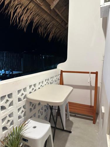 uma mesa branca e um banco numa varanda em Hiraya Baler Beachfront Cabanas em Baler