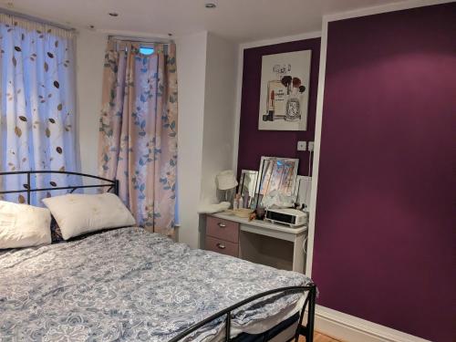 a bedroom with a bed and a purple wall at Nice place in Southport