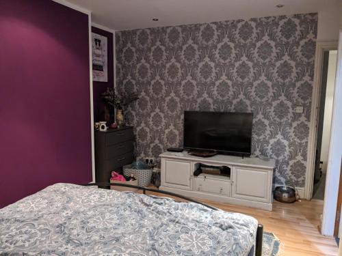 a bedroom with a bed and a tv on a wall at Nice place in Southport
