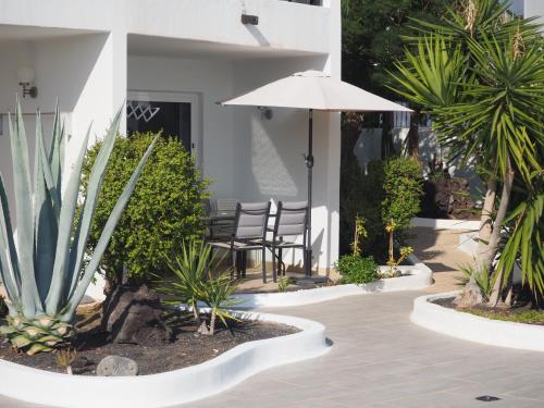 a patio with an umbrella and chairs and plants at Sea view with direct access to boulevard in Puerto del Carmen