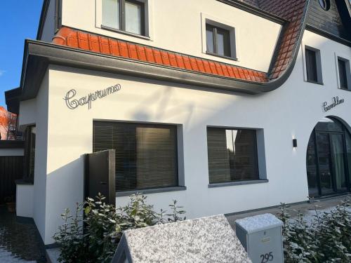 a white building with a sign on the side of it at CAPRINO Guesthouse in Knokke-Heist