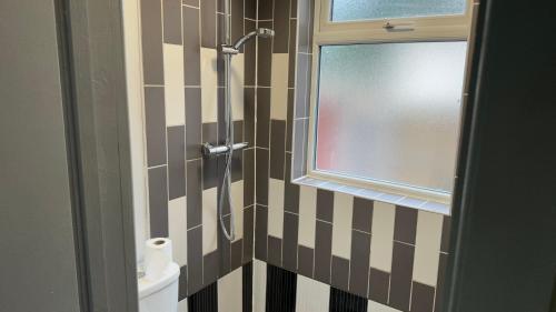 One Bedroom Apartment in Walsall Sleeps 4 FREE WIFI By Villazu في Bloxwich: حمام مع دش مع نافذة ومرحاض