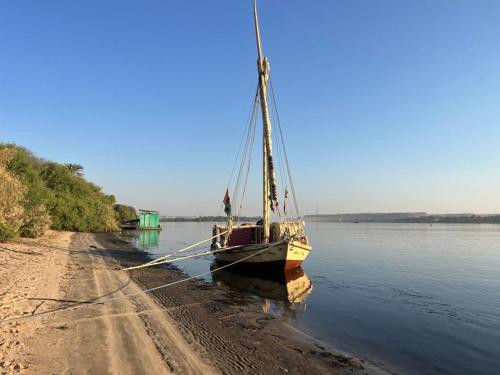 a boat sitting on the side of the water at Nile Felucca Adventure in Aswan