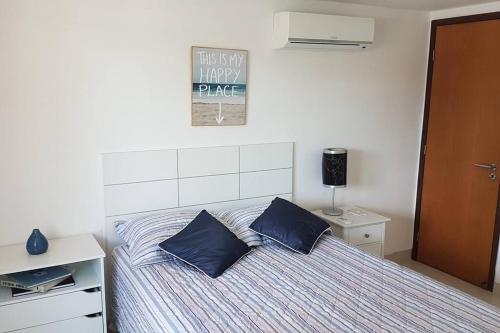 a bedroom with a bed with two blue pillows at Aconchegante Apartamento Beira-Mar (Ampla Varanda) in João Pessoa