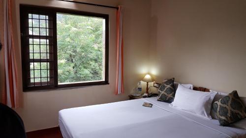 um quarto com uma cama branca e uma janela em Royal Mist Munnar em Anachal