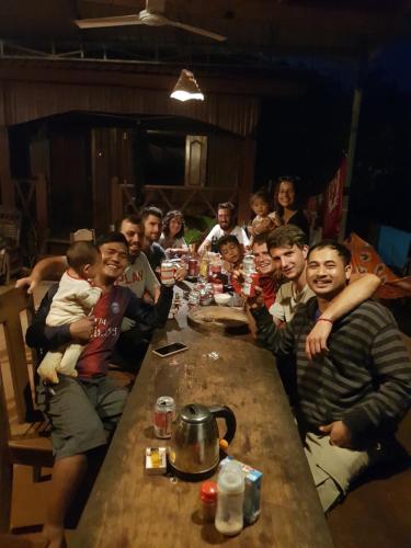 a group of people sitting around a wooden table at Banlung Mountain View Treks & Tours in Banlung