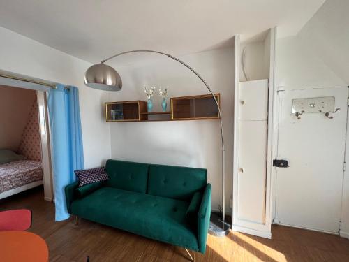 un salon avec un canapé vert et une lampe dans l'établissement Sublime Appartement Parisien, à Paris