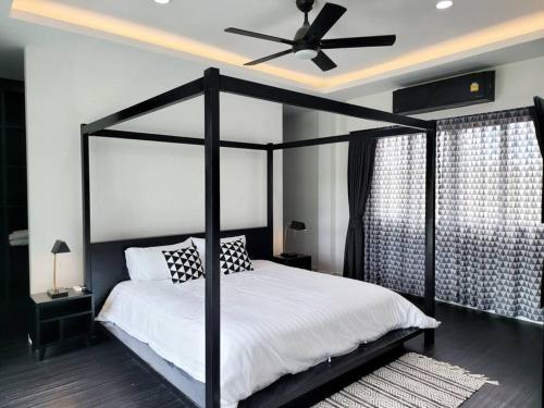a bedroom with a black canopy bed with a ceiling fan at Villa Coco in Thalang
