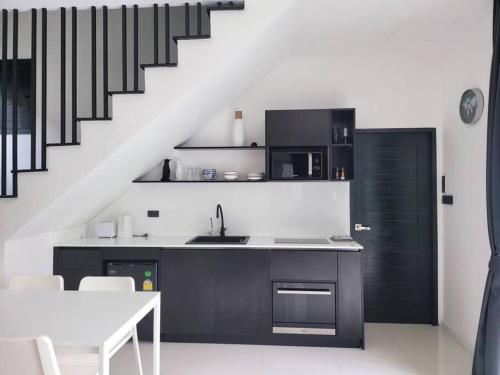 a kitchen with a sink and a counter with a staircase at Villa Coco in Thalang