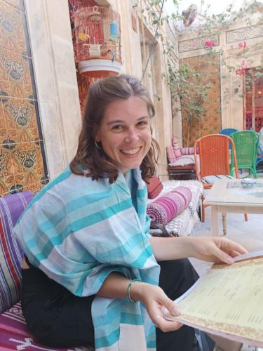 a woman smiles while sitting at a table at Dar Hkaïem in Sousse