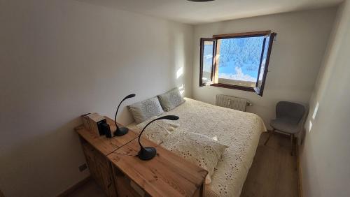 1 dormitorio con cama, mesa y ventana en Le Soladret - 2 pièces 4 étoiles - Vue extraordinaire sur les Aravis en La Clusaz