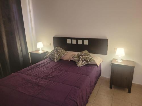 a bedroom with a purple bed with two lamps at Apartamento funcional en residencial con piscina en inmejorable ubicación en centro de la isla in Caleta De Fuste