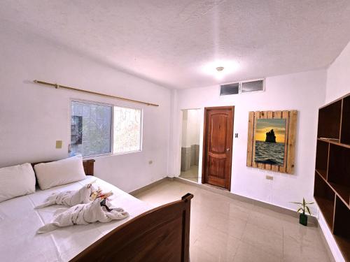 Lovely Inn في سان كريستوبال: غرفة نوم بسرير وملاءات بيضاء ونافذة
