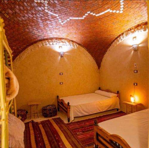 a room with two beds and a brick wall at Siwa Palace Lodge in Siwa