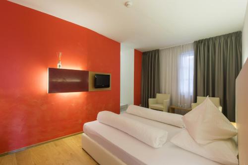 Habitación de hotel con sofá blanco y pared roja en Hotel Goldener Stern, en Caldaro