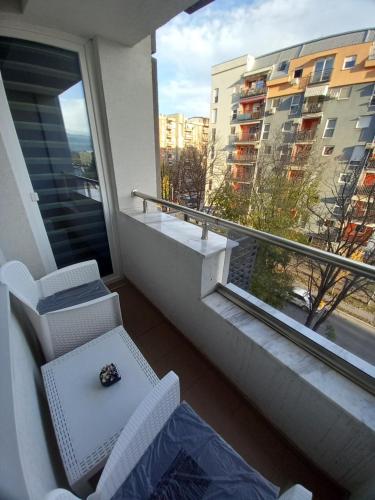 a room with a balcony with two chairs and a watch at Apartman Mircevski in Skopje