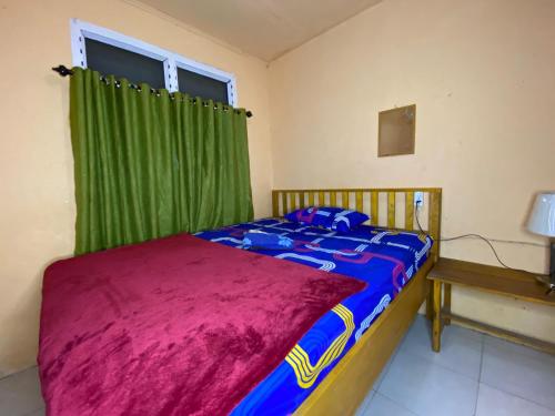 Harry & Mimin Homestay في جورونتالو: غرفة نوم بسرير وستارة خضراء