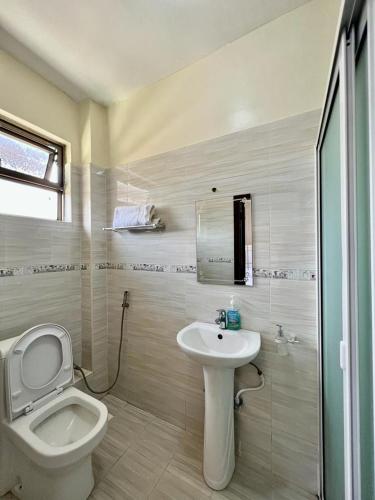 a white bathroom with a toilet and a sink at Paradise palace in Nairobi