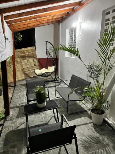 eine Terrasse mit Stühlen, Tischen und Topfpflanzen in der Unterkunft COIN D ARMANTINE in Capesterre-Belle-Eau