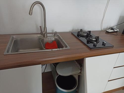 a kitchen counter with a sink and a stove at Homey Homestay at Citraland Cirebon in Cirebon